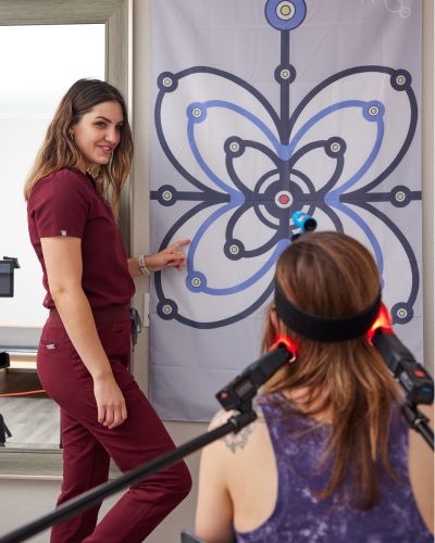 Chiropractor guiding patient through vestibular therapy with visual tracking exercise.